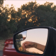 Reflection in car side mirror of an arm hanging out the window